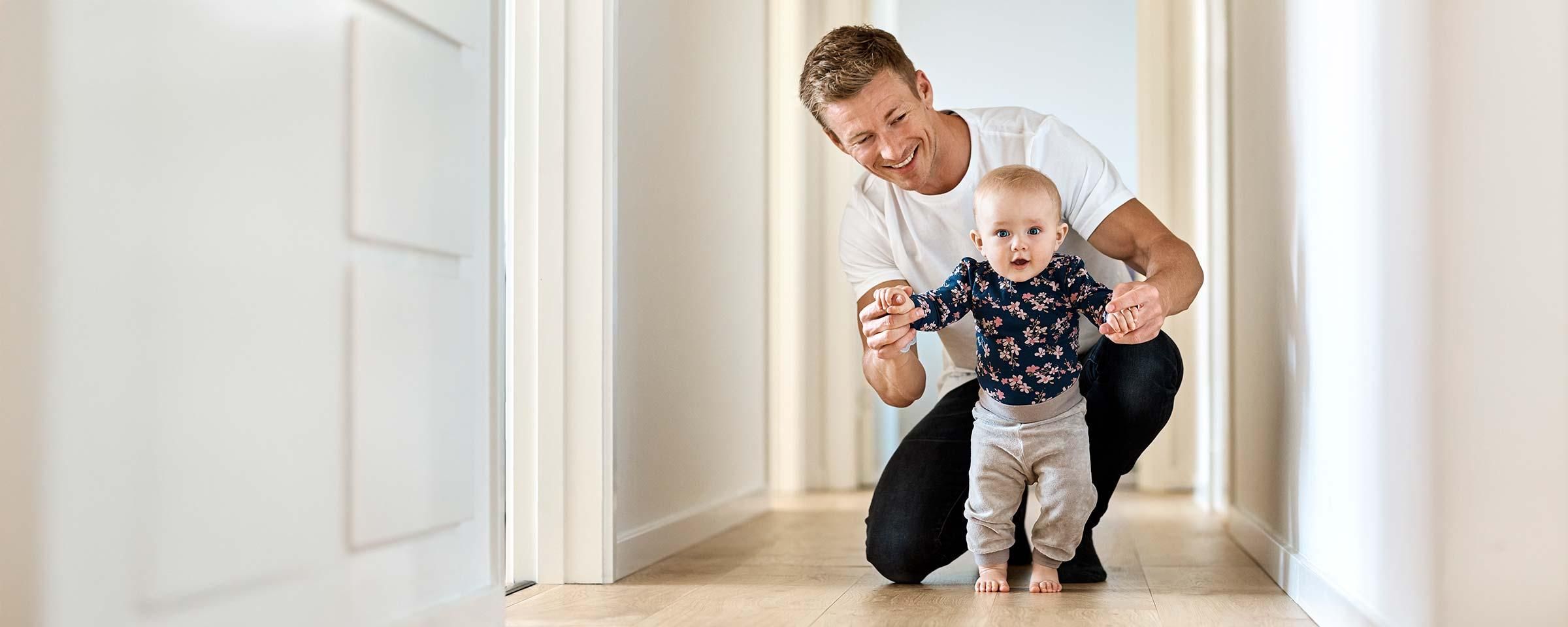 Vater bringt seinem Kind das Laufen bei.