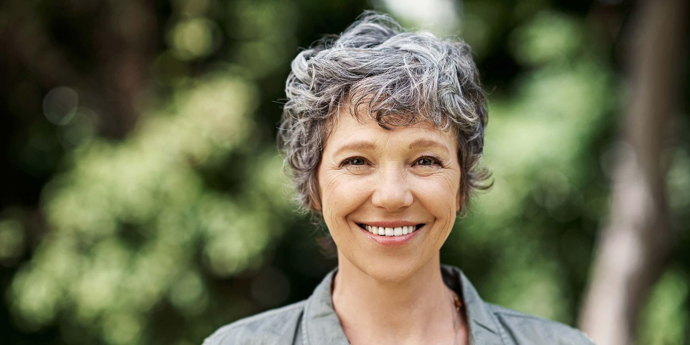 4 Frauen und 2 Männer sitzen auf einer Terrasse und lächeln in die Kamera.