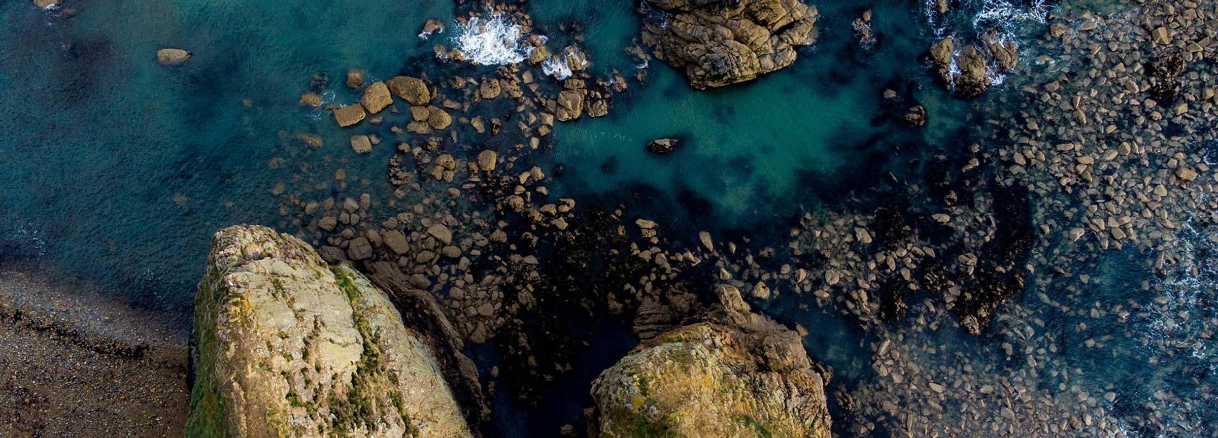 Blick auf eine Küste mit Meer und Felsen aus der Luft aufgenommen